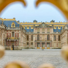 Blick durch die goldenen Tore auf den Eingangsbereich des Schloss Versailles bei Paris
